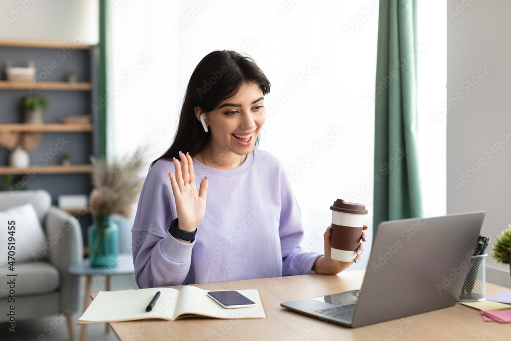 Cheerful woman having video call using pc and waving Cheerful woman having video call using pc and waving