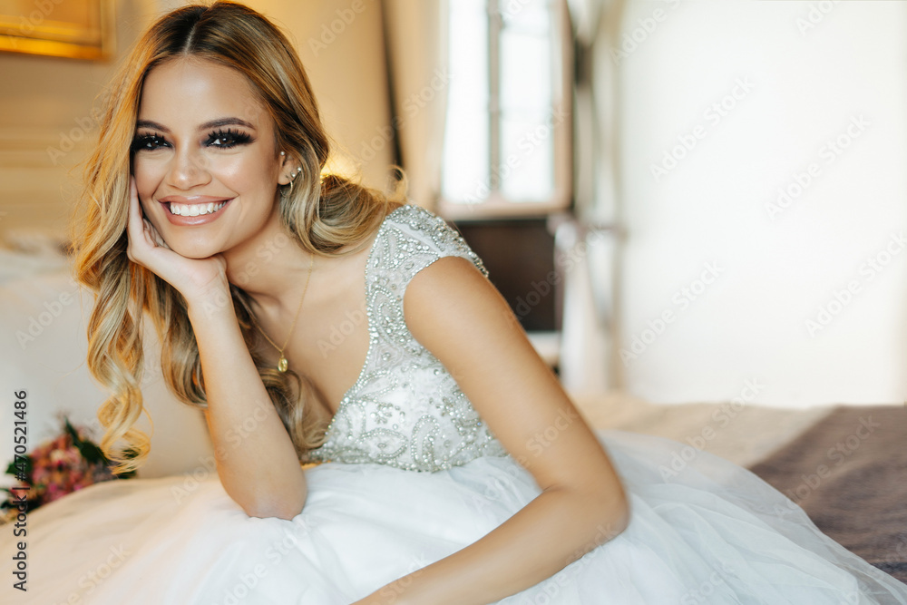 Charming bride with flowers sitting on bed Charming bride with flowers sitting on bed