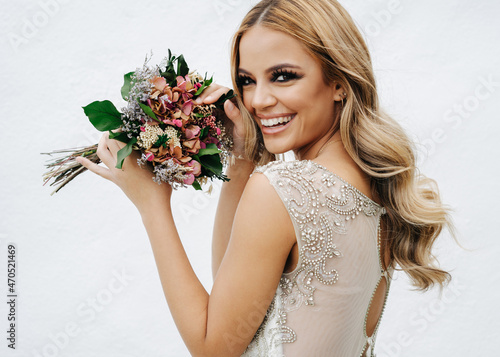 Happy bride with bouquet near wall photo