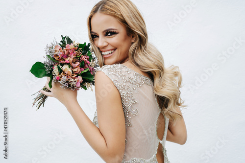 Happy bride with bouquet near wall