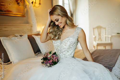 Charming bride with flowers sitting on bed photo