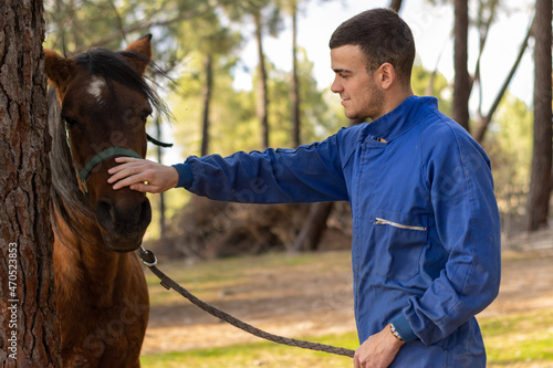 portrait of a young farmer petting his horse