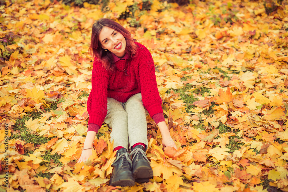young happy woman in red sweater sitting in colorful autumn leafs young happy woman in red sweater sitting in colorful autumn leafs