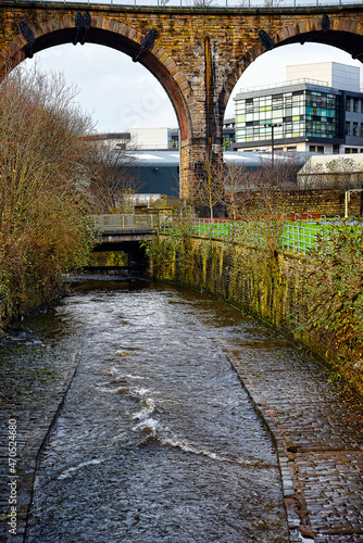 The Railway Viaduct over the conjoined Rivers Brun and Calder in Burnley with Burnley College in the background
