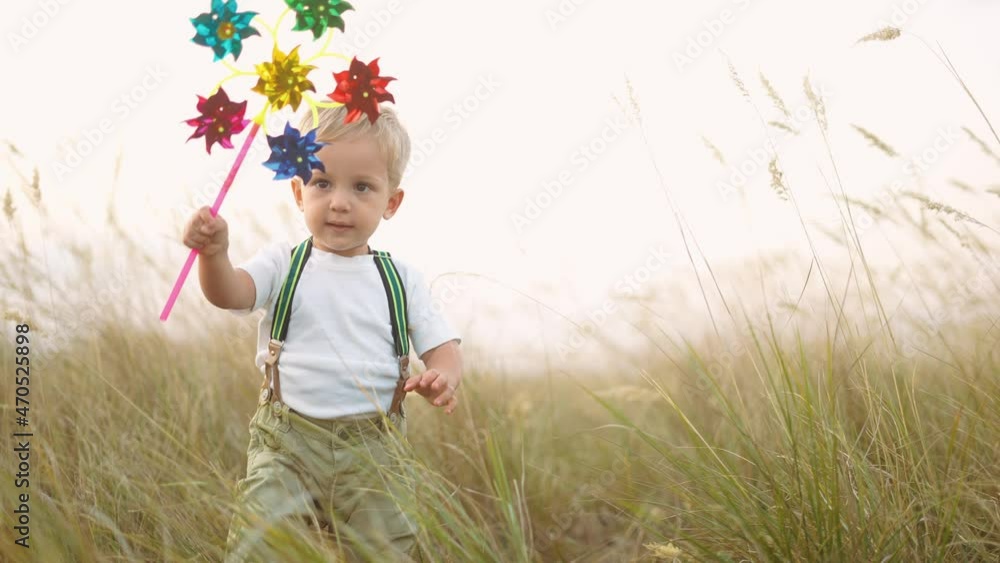 kid walk pinwheel. little baby boy play with windmill toy wind in the park. happy family kid dream concept. baby boy play toy pinwheel walk the glare sun of sunset at fun in the park kid walk pinwheel. little baby boy play with windmill toy wind in the park. happy family kid dream concept. baby boy play toy pinwheel walk the glare sun of sunset at fun in the park
