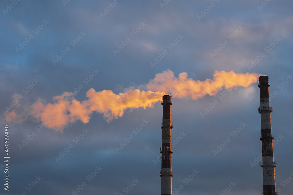 Chimney of a thermal power plant in evening light, the smoke extracted by a thermal power plant on the chimney, in the production process. Environment, pollution.