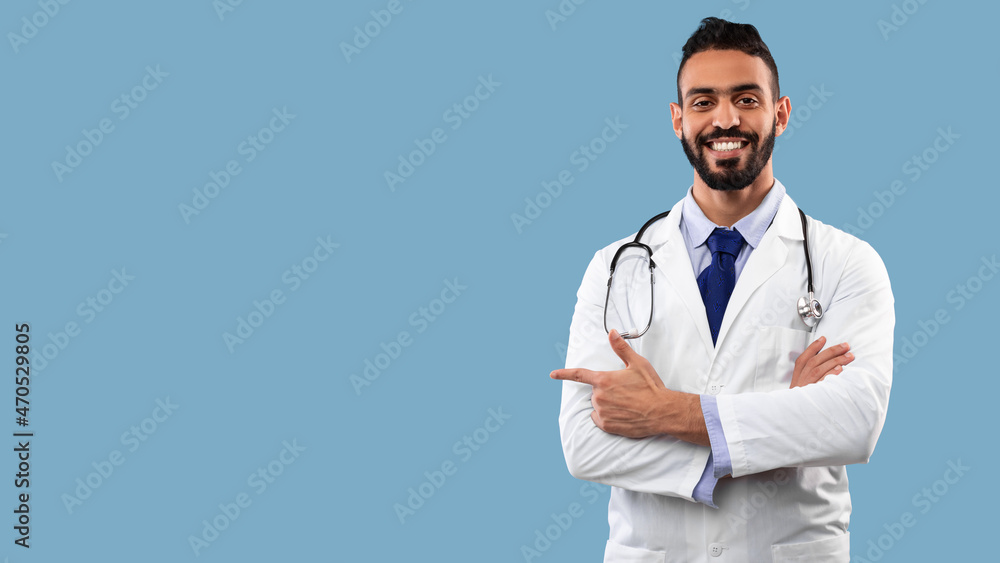 Middle-Eastern Male Doctor Pointing Finger Aside At Copyspace, Studio Shot