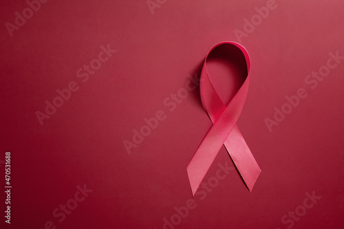Red ribbon symbol of world aids day on red background copy space