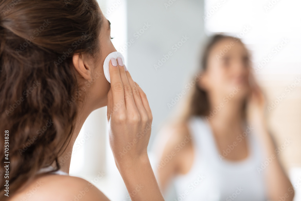 Back-View Of Woman Using Cotton Pad Looking At Mirror Indoors Back-View Of Woman Using Cotton Pad Looking At Mirror Indoors