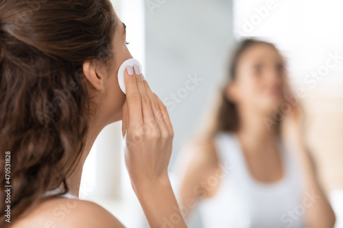 Back-View Of Woman Using Cotton Pad Looking At Mirror Indoors