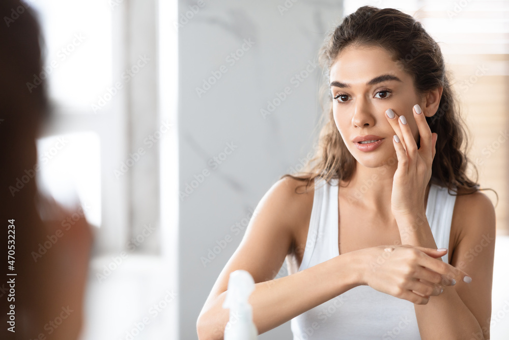 Young Woman Making Makeup Applying Foundation Standing In Bathroom Young Woman Making Makeup Applying Foundation Standing In Bathroom
