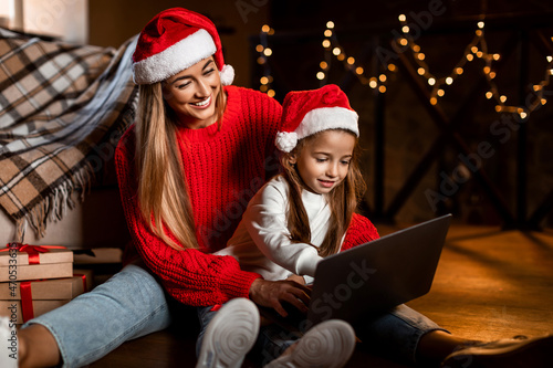 Portrait of happy festive woman and daughter using laptop