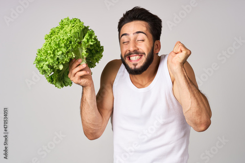 cheerful man in a white t-shirt lettuce leaves healthy food