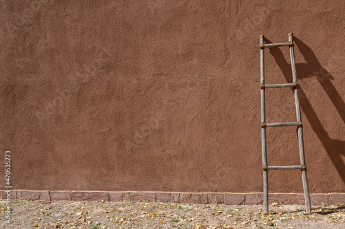 New Mexico adobe wall with ladder resting againt it photo