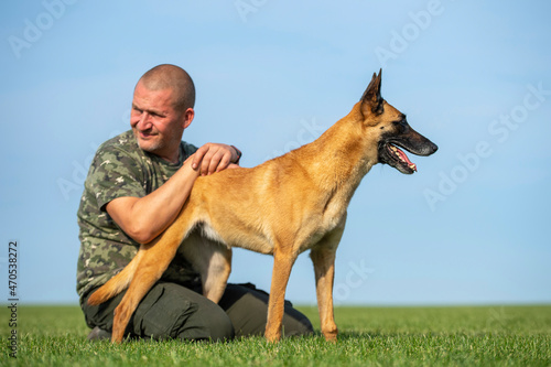 Fotografie A man in camouflage t-shirt with belgian shepherd malinois dog