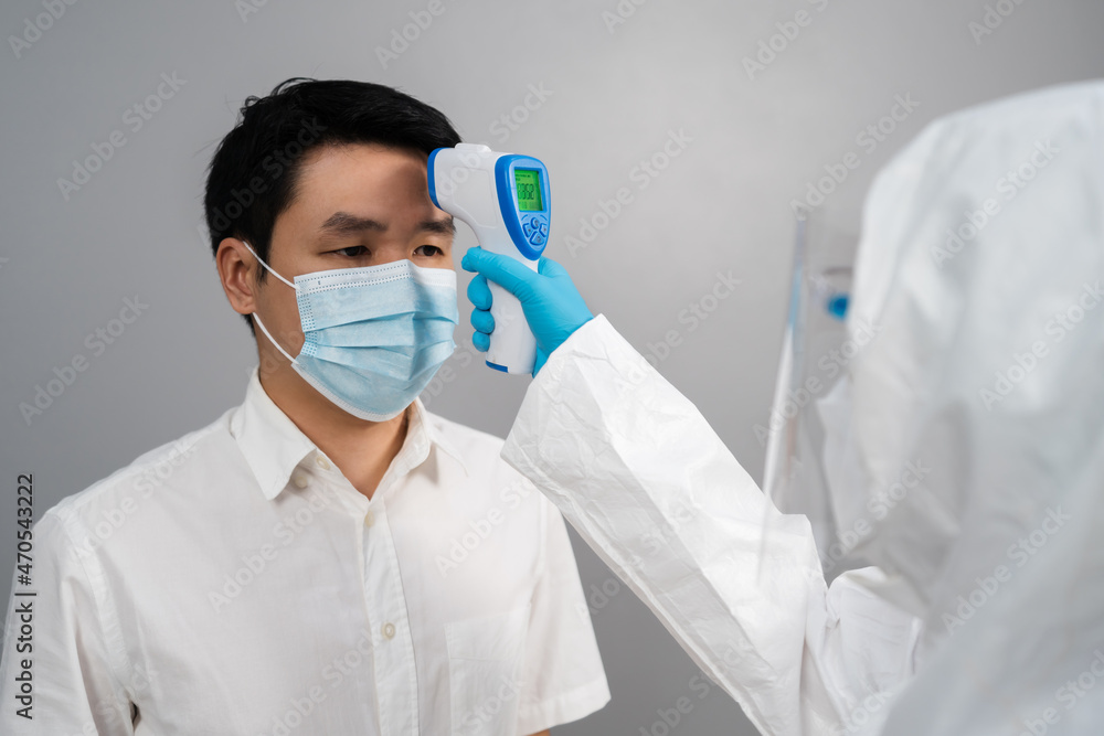 doctor in protective PPE suit using infrared thermometer measuring temperature with people doctor in protective PPE suit using infrared thermometer measuring temperature with people