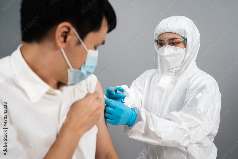doctor in PPE suit syringe and using cotton before make injection to patient in medical mask. Covid-19 or coronavirus vaccine doctor in PPE suit syringe and using cotton before make injection to patient in medical mask. Covid-19 or coronavirus vaccine