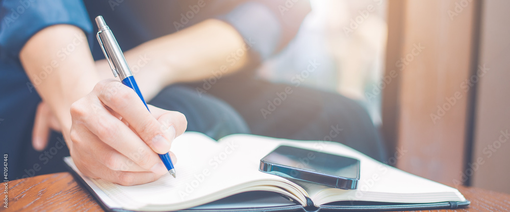 Woman hand writing on a notepad with a pen in the office.