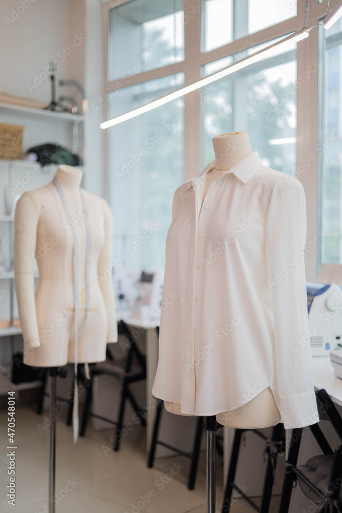 Obraz premium White handmade sewing shirt on dummy at studio sew workshop. Fashion dressmaker or seamstress