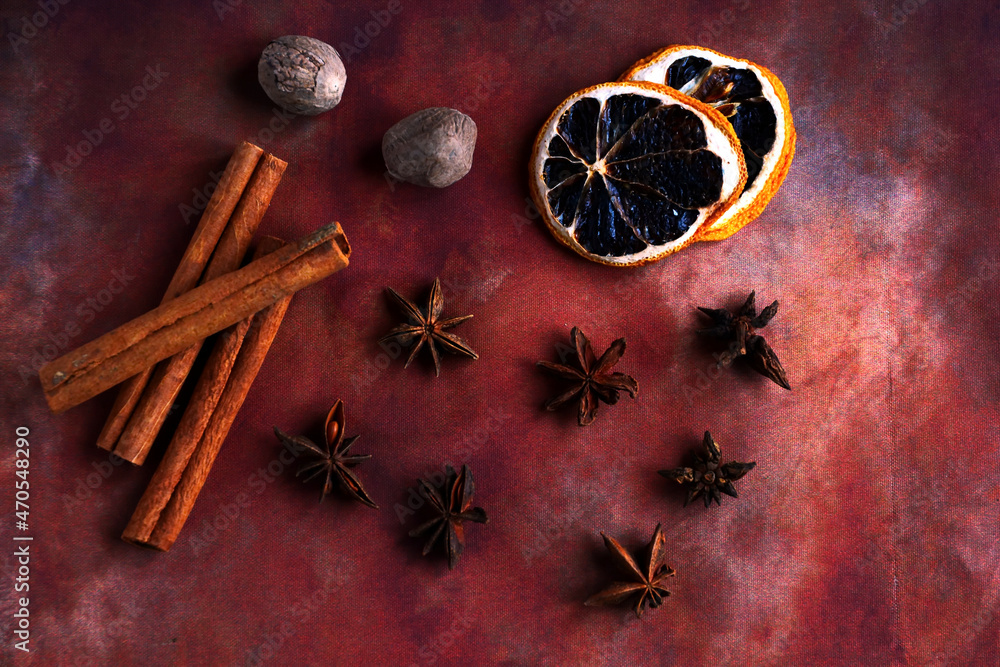 Fototapeta premium Ingredients for cooking winter drinks such as mulled wine. Cinnamon sticks, nutmeg, star anise, dehydrated lemon slices on brown background. Top view
