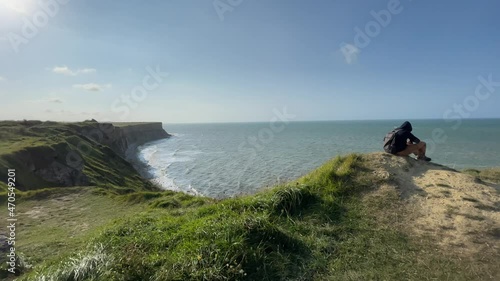 Tourist sitting on top of cliff taking photos of mulberry Harbour. View from Cap Manvieux to the historic site Normandy landings in June 6, 1944 during World War II photo