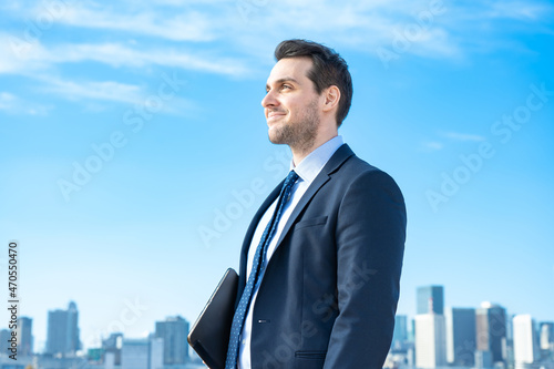青空とビル群を背景にしたビジネスマンのポートレート © maru54