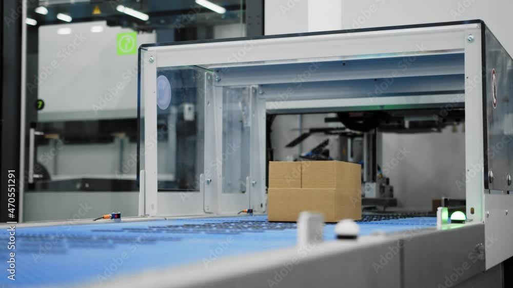 Boxes on conveyor belt fed into machine where labels are attached; mechanization Boxes on conveyor belt fed into machine where labels are attached; mechanization