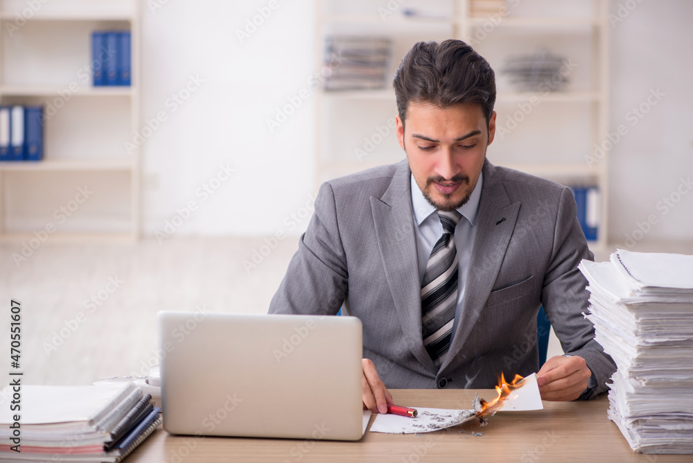 Young male employee unhappy with excessive work in the office Young male employee unhappy with excessive work in the office