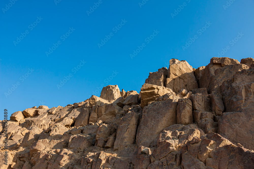 Rocks on top of a hill, clear blue sky.