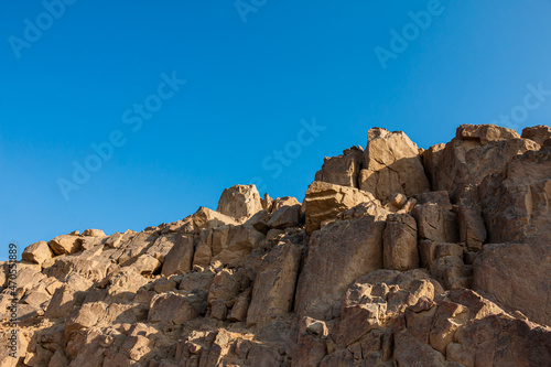 Rocks on top of a hill, clear blue sky.