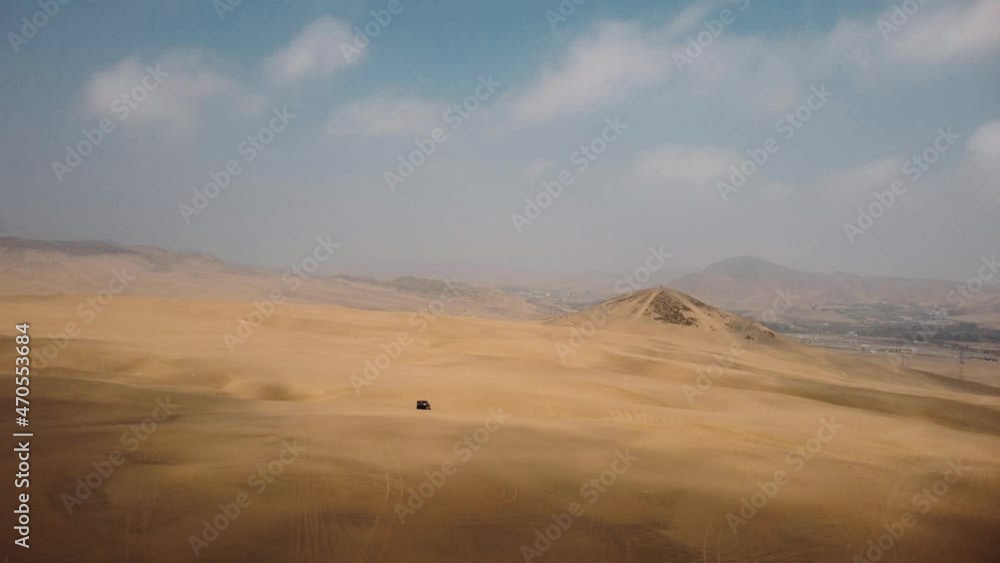 Aerial view of a off road trucks driving over dunes of Ica, Peru - pull back, drone shot Aerial view of a off road trucks driving over dunes of Ica, Peru - pull back, drone shot