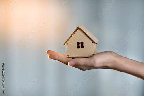 wooden small house in hand on a blue background, construction concept