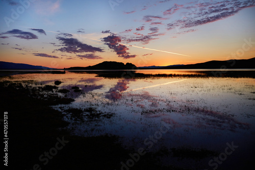 Colorful sunrise on Lake Baikal. Clouds are reflected on the surface of the water.