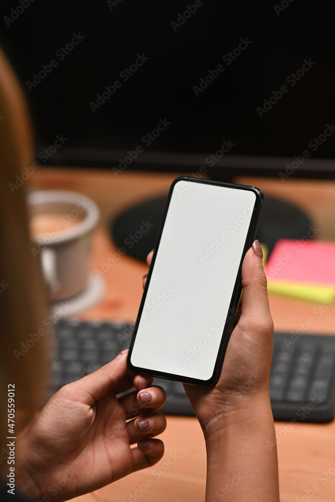 Over shoulder view of woman holding smart phone with empty display. Over shoulder view of woman holding smart phone with empty display.