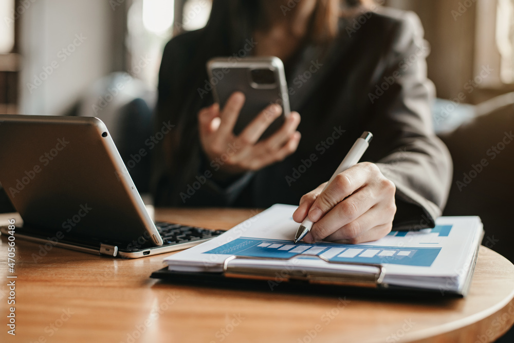 Business documents on office desk with laptop and smart phone and graph business diagram and women working at office in the morning. Business documents on office desk with laptop and smart phone and graph business diagram and women working at office in the morning.