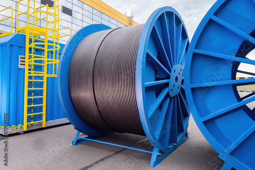 Large diameter cable reels. Power cables on metal coil. Concept - production of electrical wires. Reel for installing power cable. Electric wires are kept outdoors. Power Wire Manufacturing