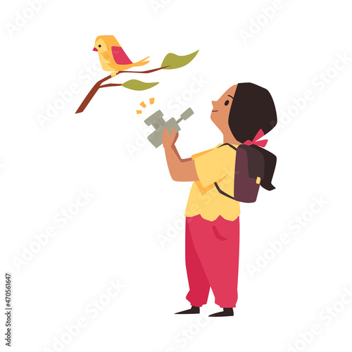 School girl explores nature, examines, photographs bird sitting on branch
