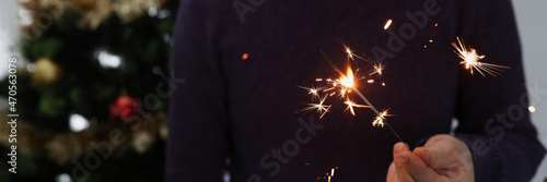 Man holds lighted sparkler in dark closeup