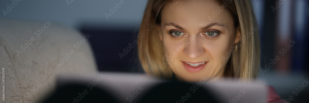 Portrait of woman in dark looks at screen of tablet Portrait of woman in dark looks at screen of tablet