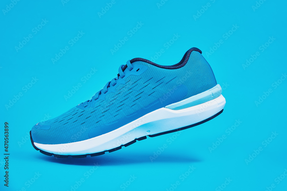 Blue running sneaker close up. Sport male shoe steps on blue background. Fitness concept Blue running sneaker close up. Sport male shoe steps on blue background. Fitness concept