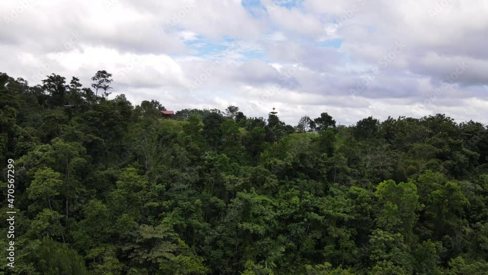 Drone circling around a small building sitting on top of a hill in deep central American rainforest. Cinematic aerial footage of authentic Costa Rican living concepts. Local flora captured in 4k. Drone circling around a small building sitting on top of a hill in deep central American rainforest. Cinematic aerial footage of authentic Costa Rican living concepts. Local flora captured in 4k.