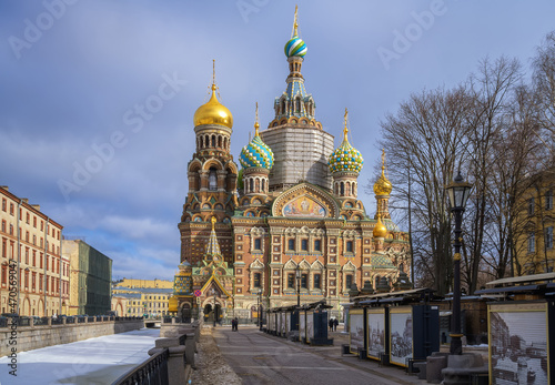 View of the Cathedral of the Savior on Spilled Blood and the Griboyedov Canal in St. Petersburg (Russia) on a winter sunny day. An old stone church with many colorful decorations. Russian architecture