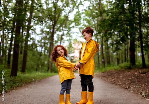 Fototapeta Naklejka Na Ścianę i Meble -  Redhead siblings in yellow raincoats in park