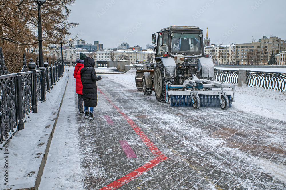 Fototapeta premium The municipal service clears the city embankment of snow on a winter day