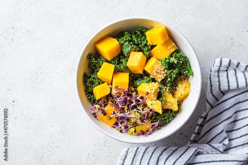 Detox salad with kale, mango and sprouts in white bowl. Vegan food, healthy plant-based diet concept.