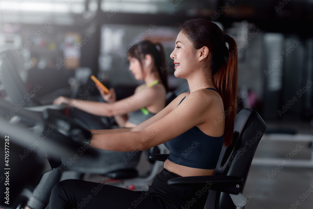 Young Asian woman working out on exercise bike at gym. Young Asian woman working out on exercise bike at gym.