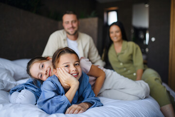 Happy young family with two children lying on bed at hotel, summer holiday.