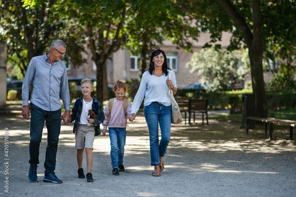 Happy grandparents taking grandchildren home from school, walking outdoors in street. Happy grandparents taking grandchildren home from school, walking outdoors in street.