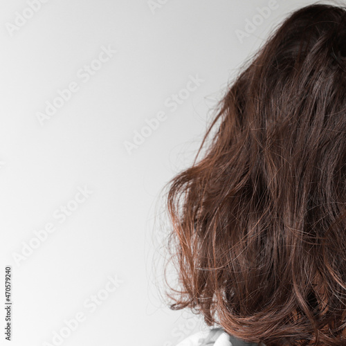 Back view of beautiful fluffy, curly medium length brunette girl. Design mockup on a gray background.