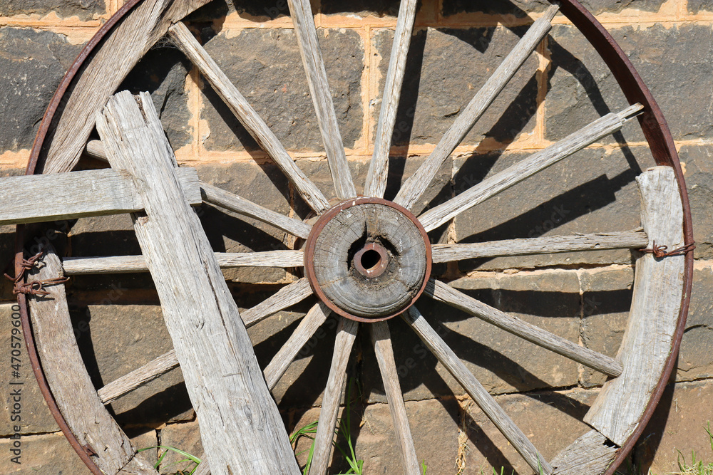 old cart wheel against stone wall